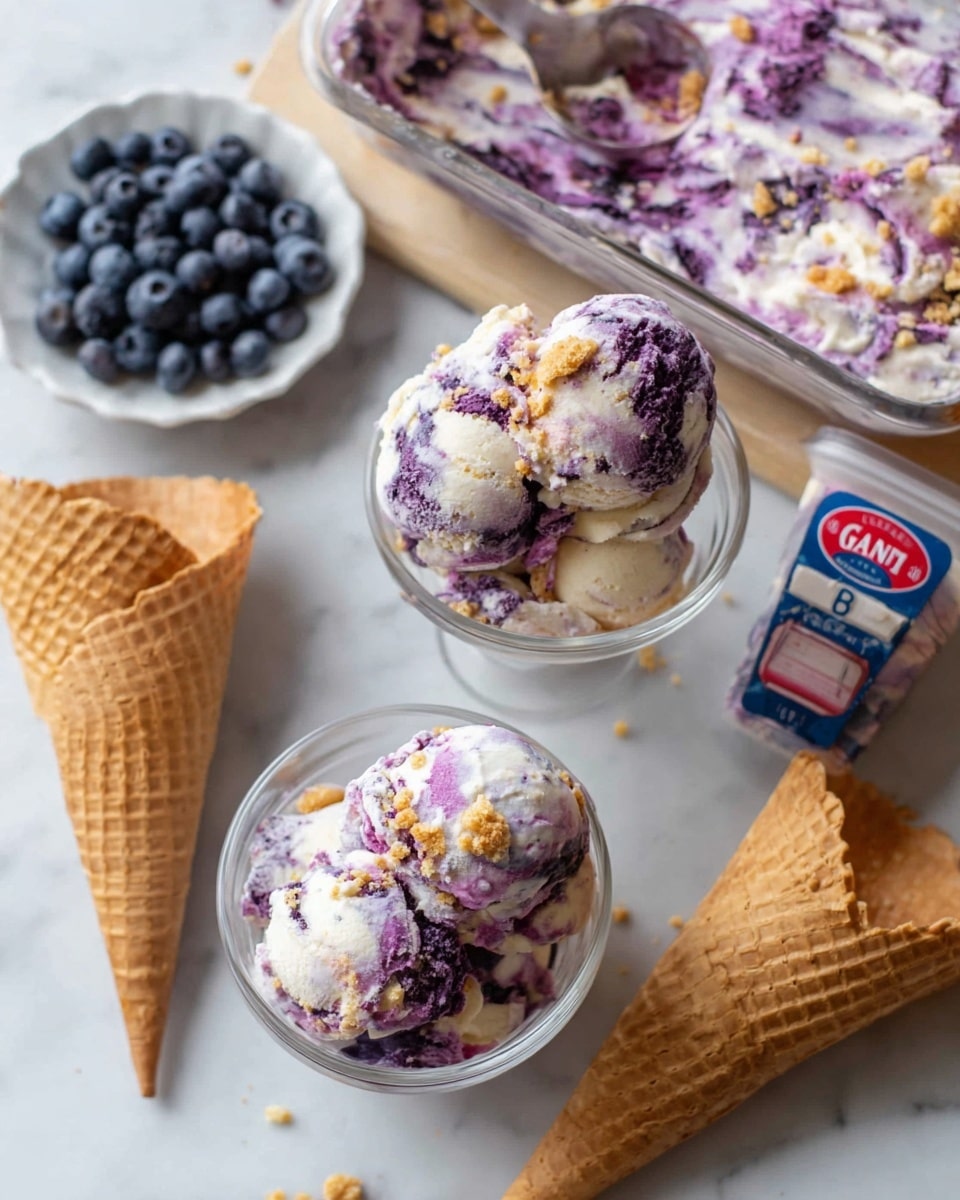 The image shows a dessert made of purple and white swirled ice cream served in two clear glass bowls and on a white plate with a waffle cone. Each bowl has two scoops of the ice cream, one bowl topped with small brown crunchy crumbs, while the other bowl shows only the ice cream. The ice cream itself is creamy with a mix of purple berry swirls and white vanilla base. On the table, there is a white plate holding a waffle cone filled with a scoop of the same purple and white ice cream, and two empty waffle cones lie next to it. A clear plastic container of fresh blueberries with a blue and red label is also placed on the white marbled surface around the ice cream items. Photo taken with an iphone --ar 4:5 --v 7