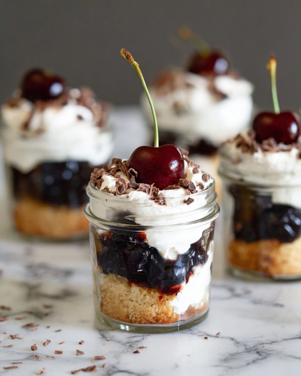 The image shows four small glass jars with a three-layer dessert inside, placed on a white marbled surface. The bottom layer is a golden-brown crumbly cake, the middle layer is a dark, thick cherry sauce with visible whole cherries, and the top layer is a fluffy white whipped cream. Each jar is topped with finely grated chocolate shavings and a single dark red cherry with a long green stem standing upright. The jars are arranged with one fully in focus in the front and three slightly blurred in the background, creating depth. Photo taken with an iphone --ar 4:5 --v 7
