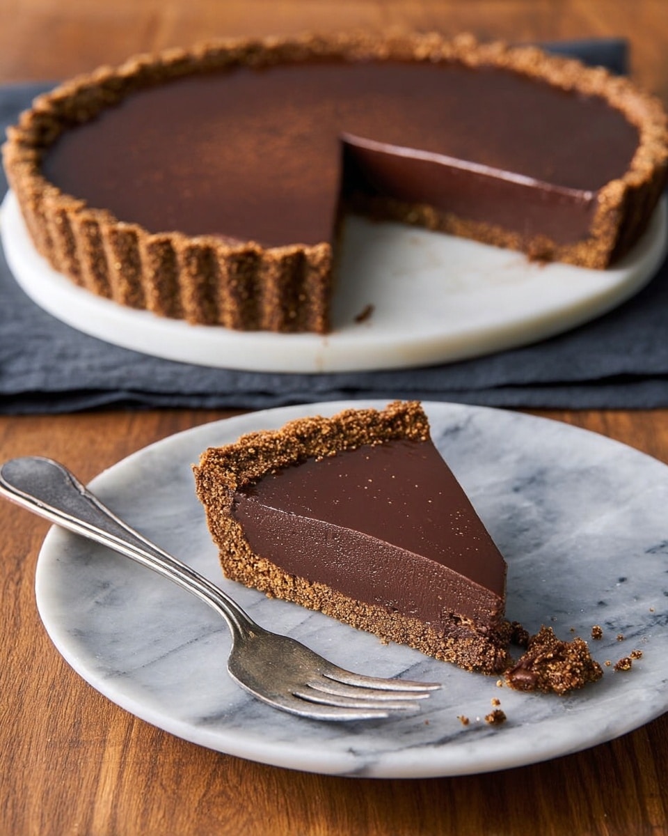 The image shows a chocolate tart with two distinct layers on a white marbled surface. The tart has a thick, crumbly brown crust with a textured edge, holding a smooth, dark brown chocolate filling that is shiny and evenly spread. A slice is cut from the tart and placed on a white plate, showing the same two layers: the crust and the smooth chocolate top with a glossy finish. A metal fork with a piece of the tart on it rests on the plate near the slice. Photo taken with an iphone --ar 4:5 --v 7