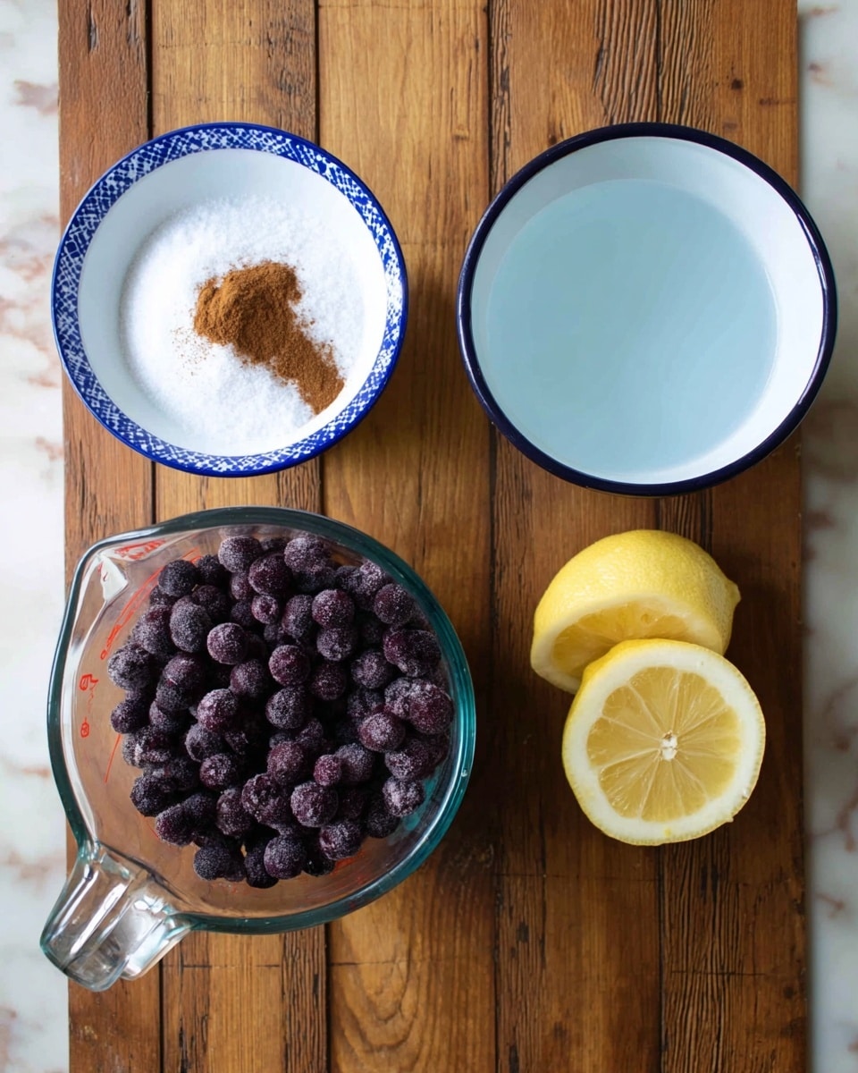 The image shows four items arranged on a wooden surface. At the bottom left, there is a clear glass measuring cup filled with dark purple frozen berries. At the top left, a white bowl with blue trim holds a pile of white granulated sugar with a small heap of brown powder, likely cinnamon, on top. To the top right, a white bowl with a blue inside design contains clear liquid, probably water. At the bottom right, there is a half lemon with a yellow peel and visible juicy sections. The background is a white marbled texture. photo taken with an iphone --ar 4:5 --v 7