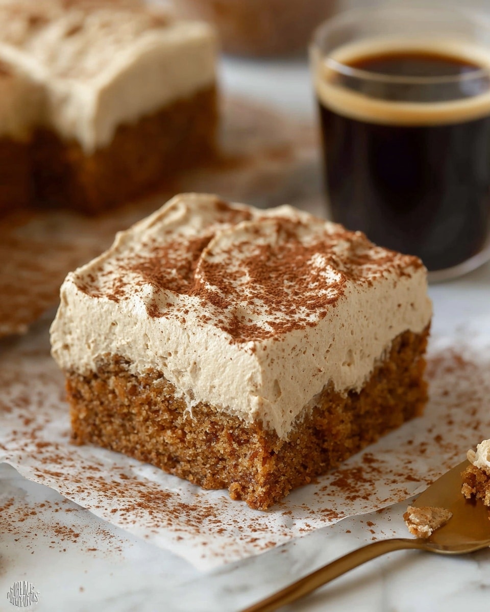 A close-up of a square piece of moist brown cake with a thick layer of light beige frosting on top, sprinkled with a light dusting of cocoa powder. The cake sits on white parchment with some cocoa powder scattered around it. Behind the cake is a clear cup filled with dark coffee and another piece of the same cake with frosting. A golden spoon with crumbs is partially visible at the bottom right corner, all placed on a white marbled surface. Photo taken with an iphone --ar 4:5 --v 7