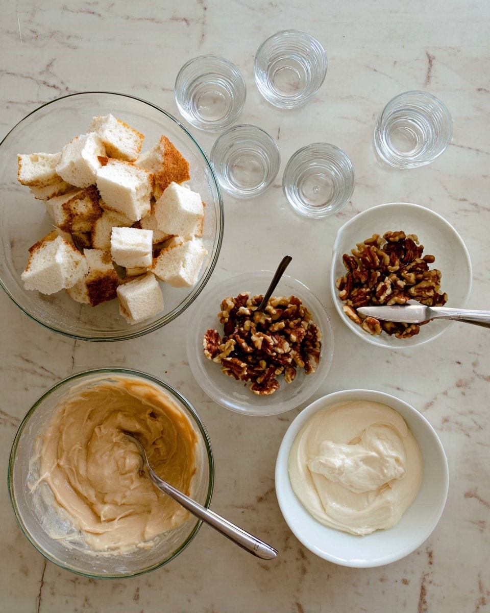 The image shows several clear glass bowls and a white bowl placed on a white marbled surface. One large glass bowl holds white bread pieces with some darker toasted parts on top. A smaller glass bowl contains brown nuts, likely pecans or walnuts. Four empty clear glass cups are arranged in a square near the bowls. A white bowl holds a light tan creamy mixture with two spoons inside, while another white bowl contains a thick white creamy substance with a spoon resting in it. The overall scene depicts ingredients ready to be assembled into a dessert or snack. photo taken with an iphone --ar 4:5 --v 7