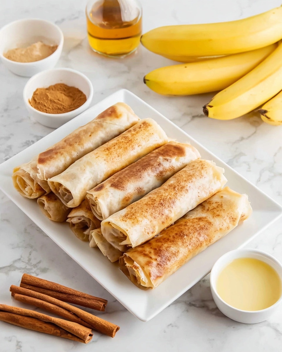 The image shows a white rectangular plate on a white marbled surface, holding six rolled pastries arranged in two neat rows of three. Each pastry is lightly browned with a range of soft tan to golden brown colors, showing smooth and slightly crinkled textures on their thin, crispy skin. Around the plate, there are small white bowls containing light brown powder, yellow butter, and beige sauce, a bunch of cinnamon sticks, a bottle with clear liquid, and two whole yellow bananas, all set on the white marbled surface. photo taken with an iphone --ar 4:5 --v 7