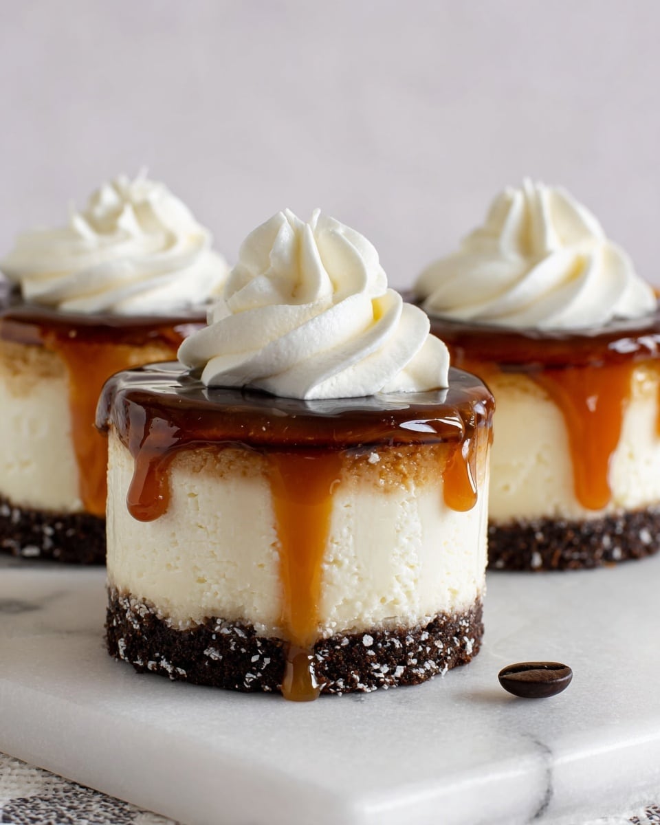 The image shows three small round cheesecakes on a white marbled surface. Each cheesecake has three clear layers: the bottom is a dark brown crumbly crust, the middle is a thick creamy white cheesecake layer, and the top is a shiny caramel sauce dripping slightly down the sides. On top of each caramel layer, there is a small swirl of smooth white whipped cream. A single dark coffee bean lies near the cheesecakes on the surface. The photo taken with an iphone --ar 4:5 --v 7