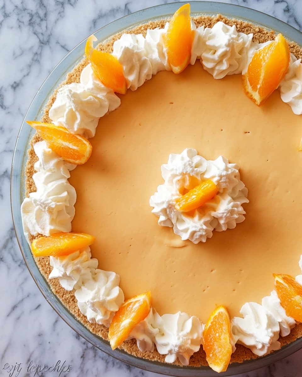 A round pie with one main smooth layer of light orange filling sits in a clear pie dish on a white marbled surface. The crust is thin and light brown, holding the filling. Around the edge of the pie, there are white swirls of whipped cream evenly spaced, each topped with a small yellow-orange slice. In the center of the pie, there is a circle made of white whipped cream with one small yellow-orange slice on top. The colors are soft: light orange for the main layer, white for the whipped cream, and yellow-orange for the fruit slices. Photo taken with an iphone --ar 4:5 --v 7
