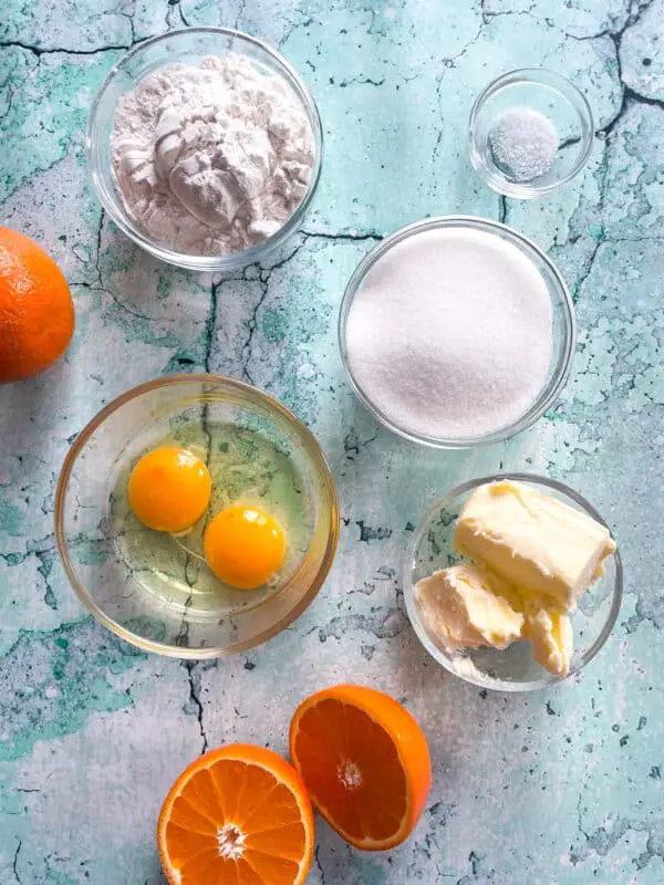 Several clear glass bowls are placed on a white marbled surface, each holding a different ingredient for baking. The top left bowl contains white flour with a powdery texture. To the right of it is a small bowl filled with coarse salt. Below the salt bowl is a medium-sized bowl filled with white granulated sugar. Near the bottom right is a small bowl with softened yellow butter. At the bottom left, there is a clear bowl containing two raw eggs with bright yellow yolks and translucent whites. In the bottom center of the image, a bright orange is halved horizontally, showing its juicy inner segments. The whole layout is evenly lit and arranged for a clear view of each ingredient. Photo taken with an iphone --ar 4:5 --v 7