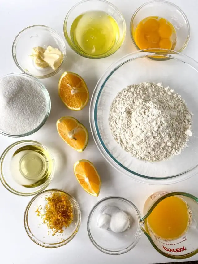 A top-down view of nine small clear glass bowls arranged on a white marbled surface. The largest bowl is filled with white flour and placed on the right side, next to a clear glass measuring cup with bright orange juice on the bottom right. Above the flour and juice are two bowls, one with three raw egg yolks and another with a pale yellow liquid. On the left side, there is a bowl with white sugar, a bowl with soft cream-colored butter, and a bowl with a small amount of violet-yellow zest. In the center are three orange wedges placed vertically in a line. The bottom middle bowl contains two white round pieces, likely salt and baking powder. The photo taken with an iphone --ar 4:5 --v 7