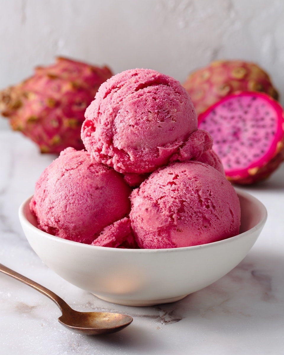 A clear glass dessert cup holds five round scoops of bright pink ice cream stacked closely together. On top of the ice cream, there are three green apple slices standing upright and leaning against the scoops. Next to the apple slices is a small bunch of fresh green mint leaves. The cup sits on a light wooden surface, with a silver spoon lying nearby to the lower right. The background is a white marbled texture. photo taken with an iphone --ar 4:5 --v 7