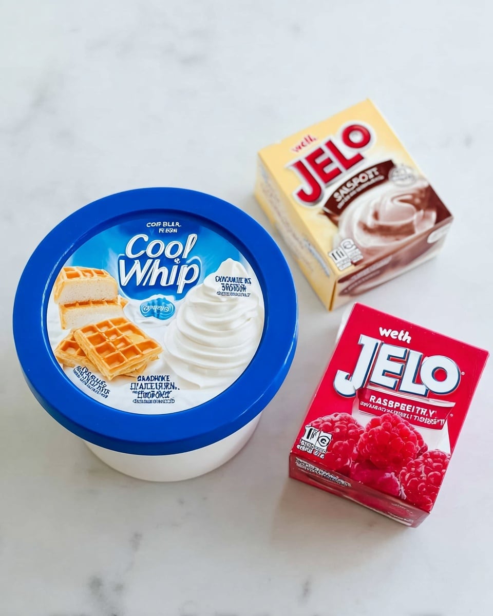 A white round container of Cool Whip Original with a blue lid featuring images of whipped topping on waffles, cake, smoothie, hot chocolate, and fruit, sits on a white marbled surface. To the right of the container, there are two small boxes of JELL-O, one vanilla flavored in light beige and the other raspberry flavored in bright red with raspberries pictured on it. The items are arranged neatly in a triangle shape, with the Cool Whip container on the left and the two JELL-O boxes stacked vertically on the right. Photo taken with an iphone --ar 4:5 --v 7