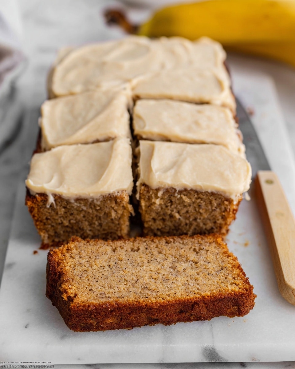 A rectangular banana cake is placed on a white marbled surface, base layer showing a moist, speckled brown texture, topped with a thick, creamy light beige frosting layer that is spread unevenly but smoothly. The cake is cut into seven pieces with three pieces pulled slightly forward, showing the soft inside and consistency of the cake. There is a banana in the blurry background and a knife with a light wooden handle is placed to the right side of the cake. Photo taken with an iphone --ar 4:5 --v 7