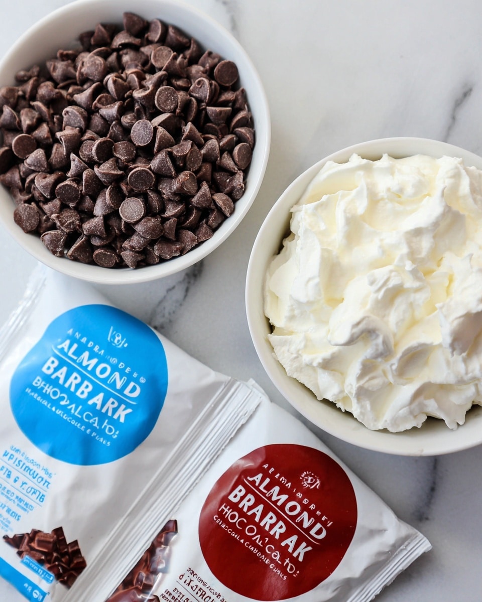 A close-up image showing two white bowls on a white marbled surface; the bowl on the left is filled with small, dark brown chocolate chips that have a smooth texture with a slight sheen, while the bowl on the right contains a fluffy, white whipped cream with a soft, creamy texture. Below the bowls, two packets labeled