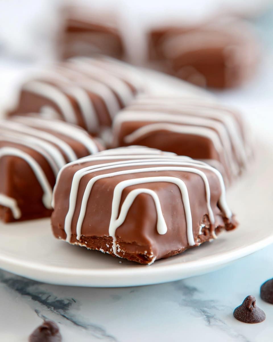 The image shows a close-up of square chocolate treats placed on a white plate over a white marbled surface. Each chocolate piece is covered in smooth milk chocolate, with three thin, wavy white chocolate lines drizzled on top, running from one side to the other. The treats are arranged in a line going slightly backward in soft focus, emphasizing the front piece. Around the plate, there are a few chocolate chips scattered for added detail. The texture of the milk chocolate looks smooth and shiny, while the white drizzle adds contrast. photo taken with an iphone --ar 4:5 --v 7