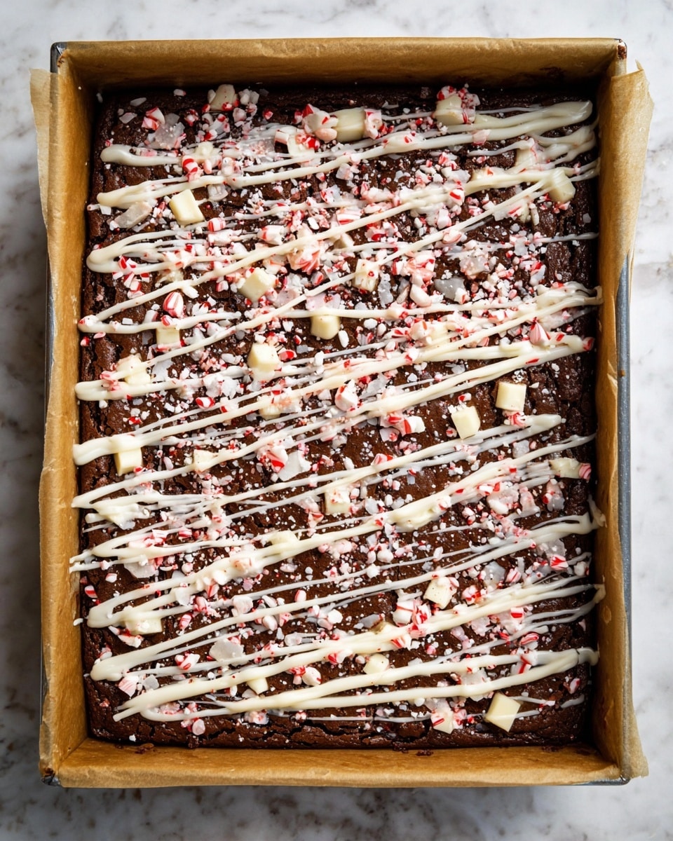 A rectangular pan holds a dark brown chocolate brownie layer covered with scattered pieces of white chocolate and crushed red-and-white peppermint candies. Over the top is a thick white icing drizzle, crisscrossed in a loose grid pattern, with some larger blobs of the icing and more crushed peppermint bits spread all over. The pan is lined with parchment paper, and the background shows a white marbled surface. photo taken with an iphone --ar 4:5 --v 7