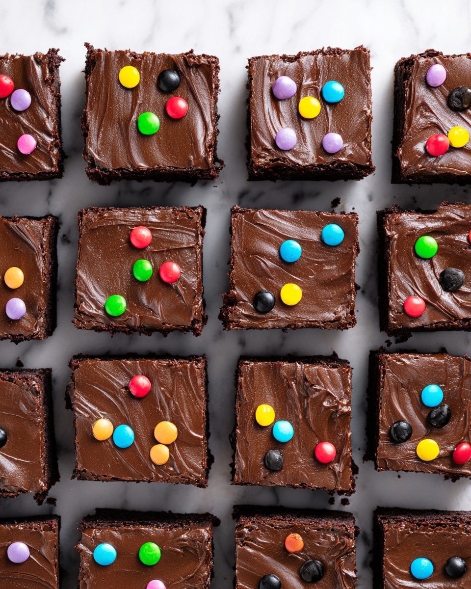 The image shows several square chocolate brownies on a white marbled surface, each with two layers: a dense, dark brown base layer with a slightly rough texture, and a smooth, glossy chocolate frosting layer on top. The frosting is decorated with small, shiny, colorful candy pieces in bright colors like green, pink, yellow, orange, blue, purple, and red scattered evenly across the top surface. The brownies appear moist and rich, and one brownie is tilted slightly, showing the thick frosting and texture clearly. Photo taken with an iphone --ar 4:5 --v 7