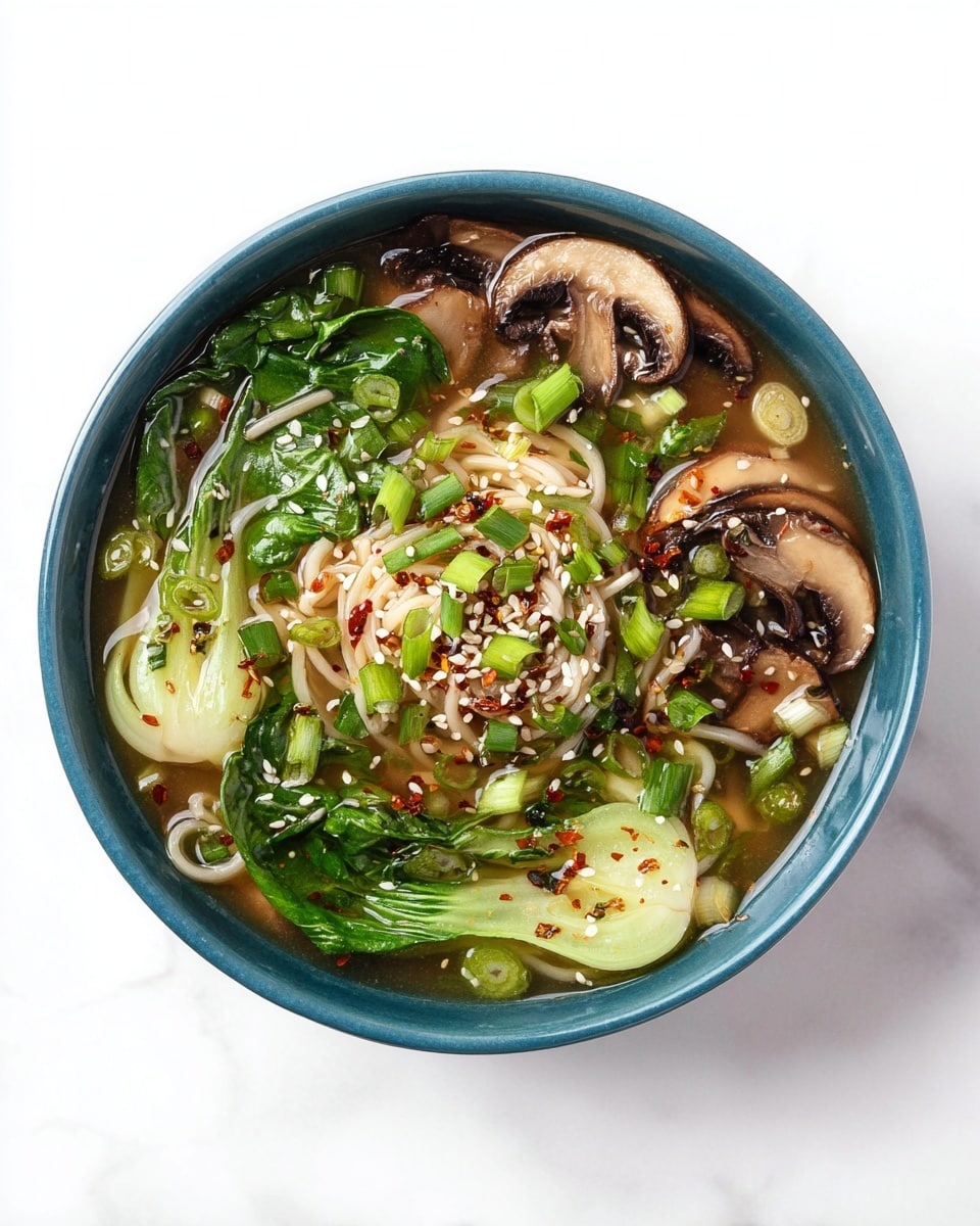 A blue bowl filled with clear broth holds several layers starting with light-colored thin noodles curled in the center. Around the noodles are green leaves of baby bok choy, green onion slices scattered all over, and sliced brown mushrooms placed evenly around the edges. The dish is sprinkled with white sesame seeds and small red chili flakes, adding texture on top. The bowl sits on a white marbled surface. photo taken with an iphone --ar 4:5 --v 7