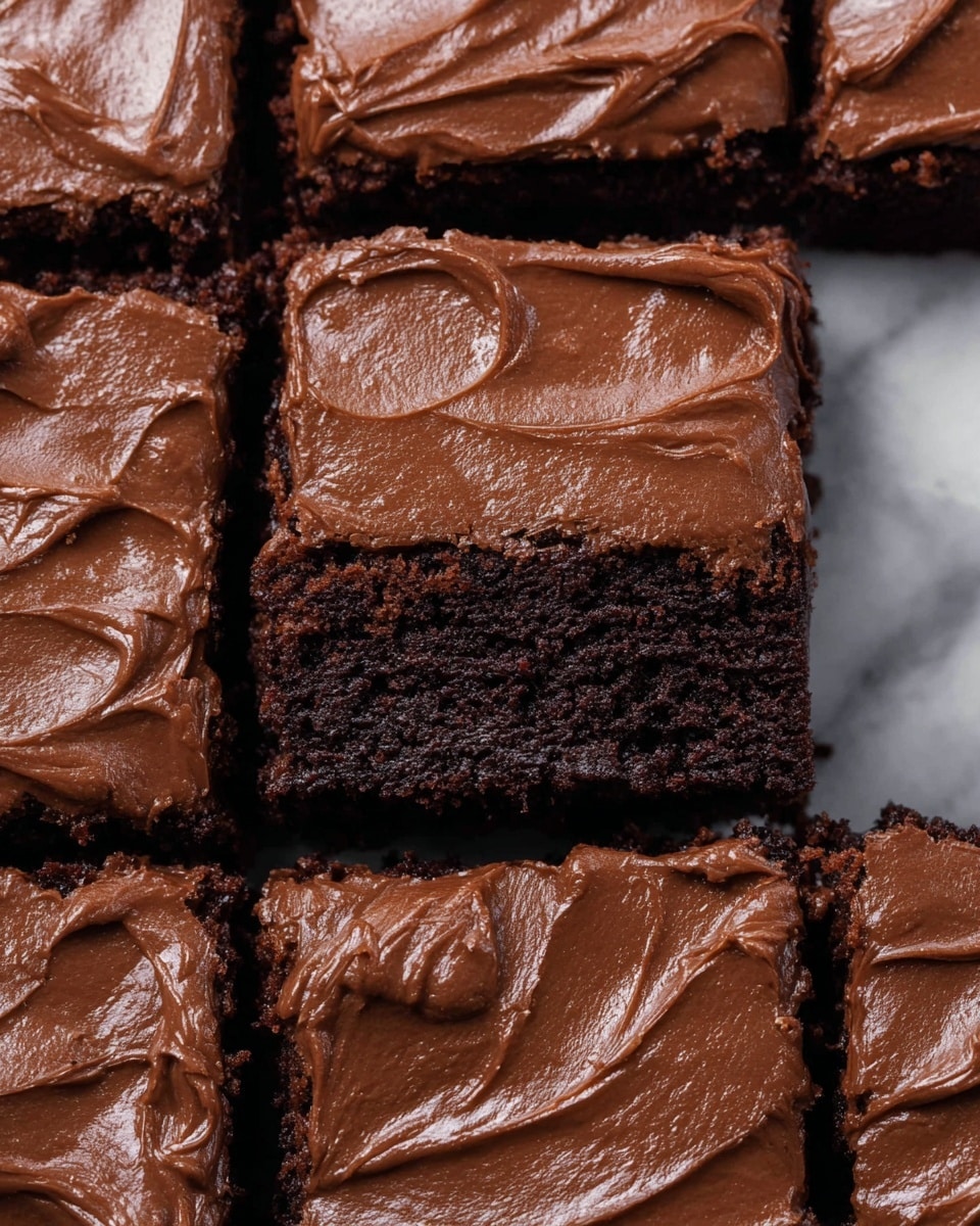 The image shows a close-up of several square pieces of chocolate brownies arranged closely together, each piece having two visible layers: a dark brown, crumbly base and a smooth, thick layer of chocolate frosting on top. The frosting is spread evenly but with slight, natural swirls and texture. The edges of the brownies are slightly rough, showing the moist interior beneath the frosting. The background is a white marbled surface. photo taken with an iphone --ar 4:5 --v 7