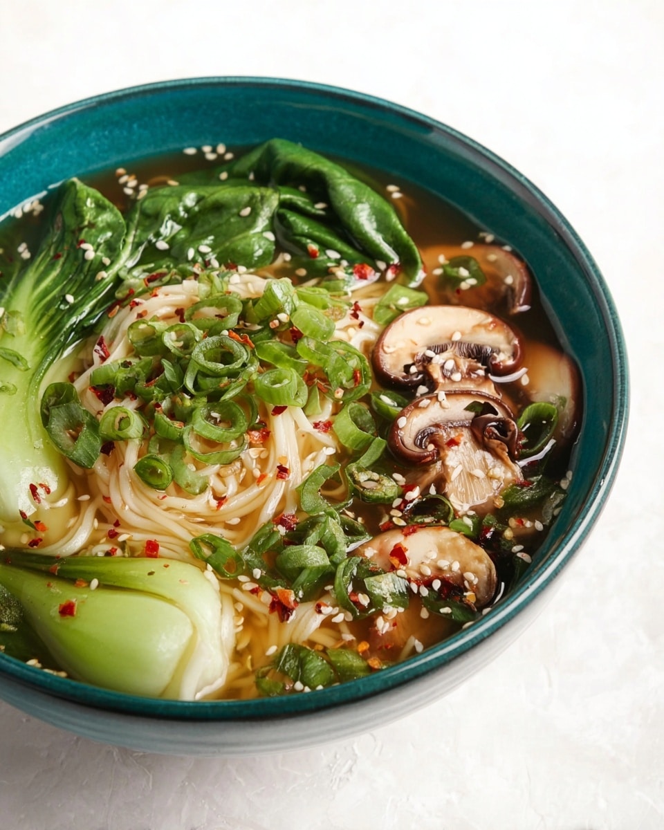 A blue bowl filled with a clear broth at the bottom, topped with pale thin noodles piled in the center, bright green baby bok choy leaves placed around the edges, light brown sliced mushrooms scattered throughout, and a generous amount of chopped green onions sprinkled on top along with white sesame seeds and small red chili flakes. The textures range from the soft noodles to the crisp bok choy and smooth mushrooms, all resting in a golden broth, with a white marbled surface underneath. photo taken with an iphone --ar 4:5 --v 7