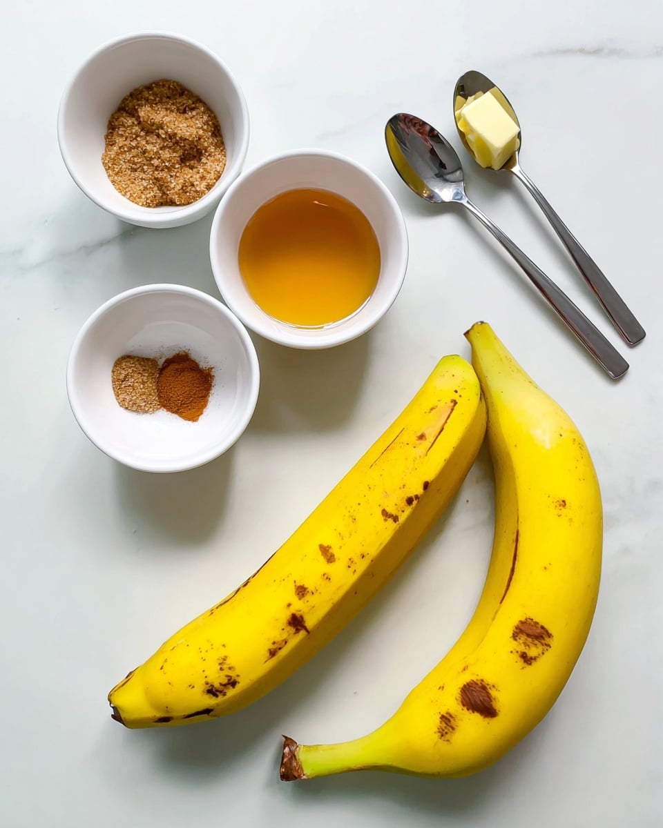 The image shows two ripe yellow bananas with some brown spots placed on a white marbled surface at the bottom center. Above the bananas, there are three small white bowls arranged in a triangle: the left bowl holds brown sugar, the middle bowl contains golden honey, and the right bowl is filled with a clear liquid, possibly water. Above these bowls, two silver spoons lie on the white marbled surface, the larger one with a small piece of yellow butter and the smaller one with a small amount of brown spice, likely cinnamon. The whole setup is simple and clean, with bright natural light. photo taken with an iphone --ar 4:5 --v 7