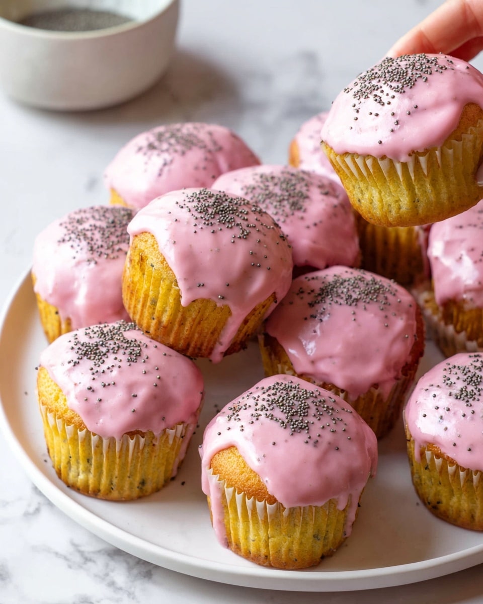The image shows a white round plate filled with ten cupcakes. Each cupcake has one layer of light golden brown cake visible at the base, topped with a thick layer of smooth, shiny pink icing that drips slightly over the edges. The icing is sprinkled with small black poppy seeds spread evenly across the surface. Two cupcakes are held above the plate by a woman's hand, showing the side texture of the cake and icing. The background has a white marbled texture with a small white bowl partially visible, holding cupcake wrappers. Photo taken with an iphone --ar 4:5 --v 7