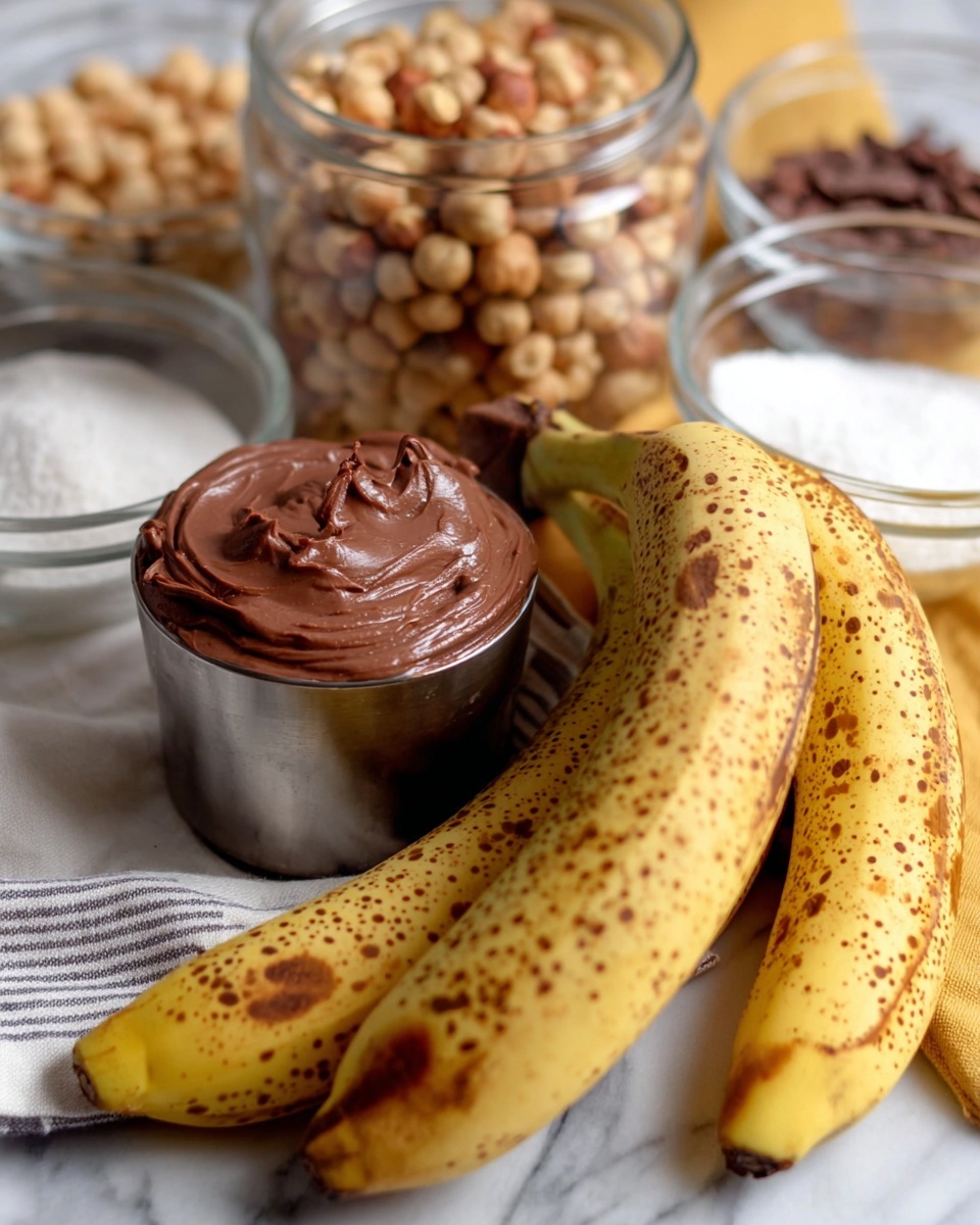 The image shows a close-up of ripe bananas with brown spots, resting on a white marbled surface. In front of the bananas, there is a metal cup filled with thick, smooth chocolate spread that has a shiny texture and soft peaks. Behind the bananas, a clear glass jar is filled with light brown hazelnuts, and next to it are glass bowls containing light brown sugar and white sugar, adding a blurred background effect. A striped cloth with white and gray tones is also partly visible beneath the metal cup and bananas, with a hint of yellow fabric beneath. photo taken with an iphone --ar 4:5 --v 7