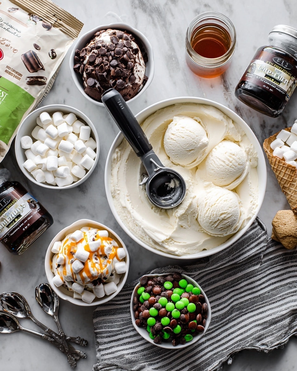 The image shows a large round white dish filled with smooth, creamy vanilla ice cream, with a black ice cream scoop resting inside. Around it, there are three small white bowls on a white marbled surface: one bowl with vanilla ice cream topped with small marshmallows, orange drizzle, and chocolate cookie pieces; another bowl with vanilla ice cream topped with brown and green round candies and chocolate syrup; and a third bowl with chocolate ice cream topped with crushed chocolate cookies and syrup. Nearby are a striped cloth, several shiny silver spoons, a bottle of chocolate syrup, a small jar of salted caramel sauce, a container of mini white marshmallows, and a bag of mint chocolate chip cookie bites. The setting is bright and clean, with the items arranged to show a variety of ice cream toppings. Photo taken with an iphone --ar 4:5 --v 7