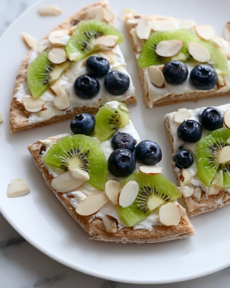 The image shows a white plate holding three slices of a fruit flatbread. Each slice has a base layer of light brown bread with a soft texture. On top of the bread is a smooth, creamy white layer covering the surface. The next layer features fresh fruit pieces: dark blue round blueberries and bright green kiwi slices with tiny black seeds, placed evenly on the creamy layer. Scattered thin almond slices with a light cream color and brown edges are sprinkled over the fruit and around the plate. The background is a white marbled surface that adds a clean and fresh feel to the image. Photo taken with an iphone --ar 4:5 --v 7