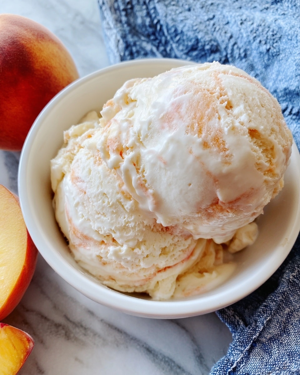 A white bowl holds two scoops of creamy ice cream with soft swirls of pale peach and white colors mixed throughout. The ice cream looks smooth yet slightly rough on the edges, showing a rich, cold texture. The bowl is placed on a white marbled surface with a blue and white cloth next to it. Two fuzzy peaches with yellow and red hues rest nearby, adding a fresh, natural touch. photo taken with an iphone --ar 4:5 --v 7
