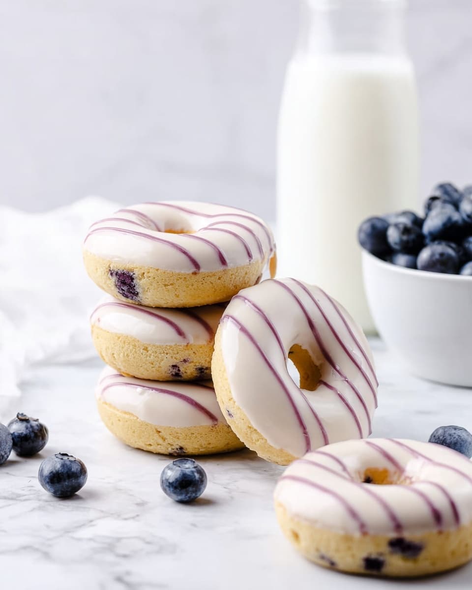 The image shows a stack of three round donuts with a slightly golden brown base and visible small dark spots inside them, likely blueberries. Each donut is topped with a smooth, white icing layer that covers the surface and is decorated with thin, even purple lines running diagonally across. One donut leans against the stack, showing the hole in the center. Nearby are two more donuts placed flat on the white marbled surface, and a few loose blueberries are scattered around. In the background, there is a white bowl filled with blueberries and a clear glass bottle filled with white milk, all set on a white marbled textured surface. Photo taken with an iphone --ar 4:5 --v 7