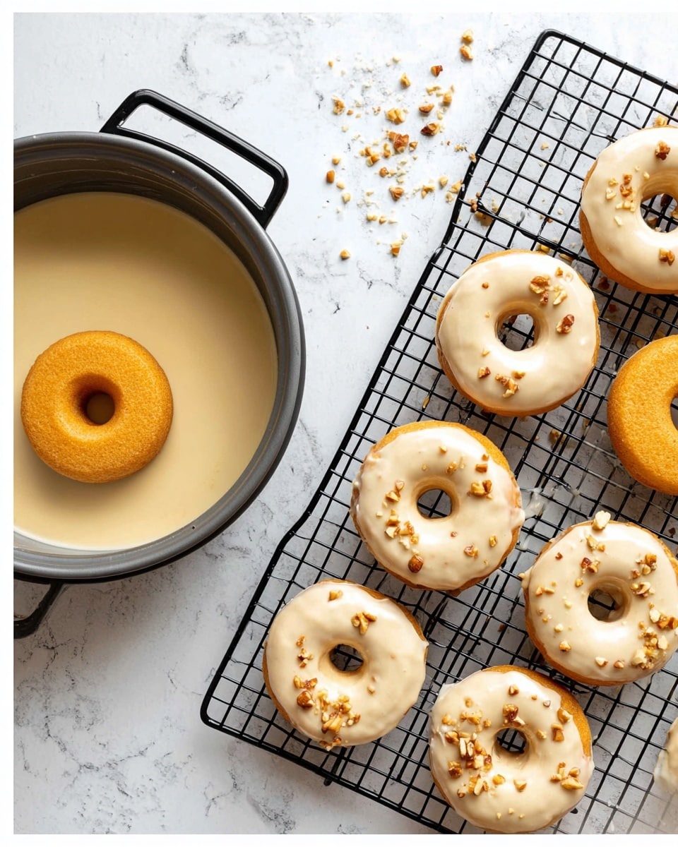 The image shows two scenes: on the left, three small golden-brown plain donuts sit on a black cooling rack on a white marbled surface. Above them is a metal pan with pale smooth batter inside, with one plain donut in the center partially dipped in the batter. On the right, six donuts are fully coated with a light cream-colored glaze and are scattered with small pieces of chopped nuts. These donuts are placed on a black wire cooling rack over a white marbled background, with some glaze drips visible on the rack. The overall scene is bright and simple. photo taken with an iphone --ar 4:5 --v 7