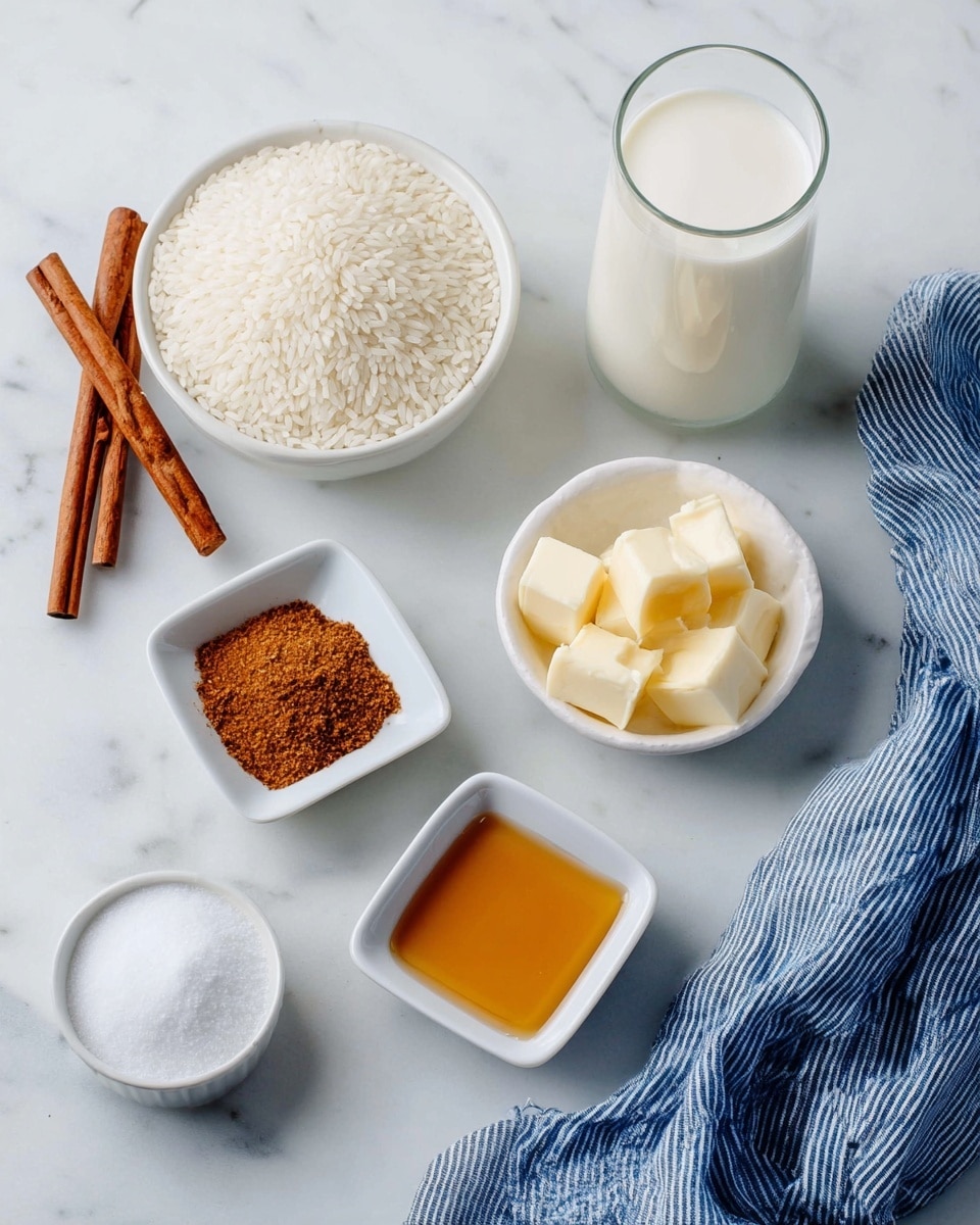 A clear glass filled with white milk stands in the middle on a white marbled surface. To the left, a white bowl holds uncooked white rice grains, and next to it, another white bowl contains white granulated sugar. Below these bowls, a small white square dish has brown cinnamon powder, and beside it, another small white square dish holds several pieces of pale yellow butter. At the bottom right, a small white square dish contains golden brown syrup. A blue and white striped cloth is folded and placed on the right side of the setup, adding a soft texture contrast. On the far left, two cinnamon sticks rest on the surface. photo taken with an iphone --ar 4:5 --v 7