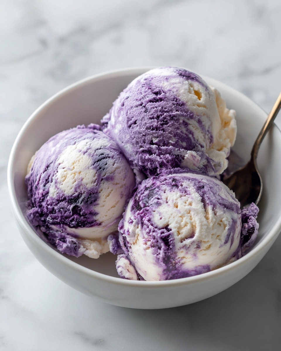 Three scoops of purple and white swirled ice cream sit closely together inside a white bowl with smooth edges. Each scoop shows a creamy, slightly rough texture with a mix of light purple and white colors blending softly. A metal spoon with a reflective surface is placed inside the bowl behind the ice cream, leaning against its side. The bowl is on a white marbled surface that shows soft grey veins. The lighting is soft and natural, highlighting the creamy texture of the ice cream and the shine of the spoon. Photo taken with an iphone --ar 4:5 --v 7