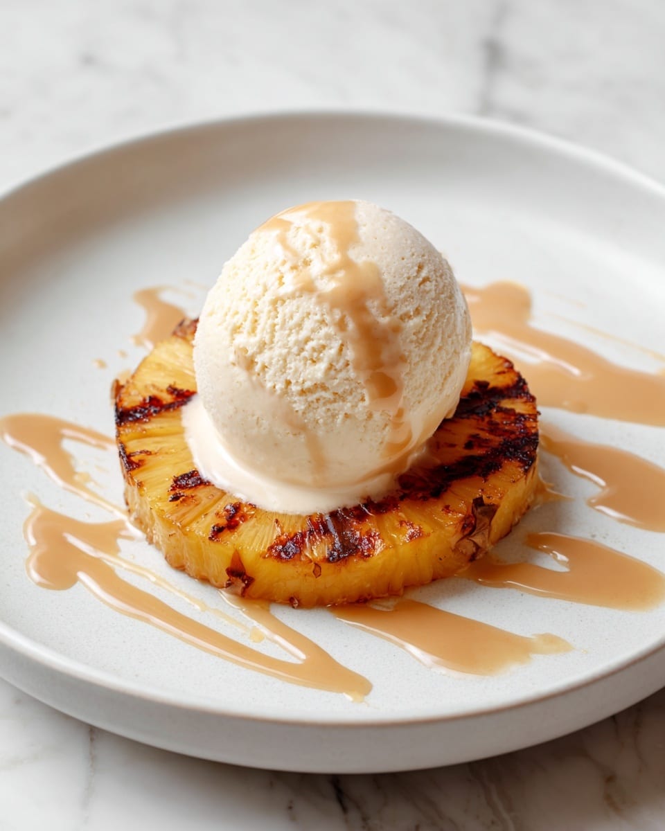 A white plate holds a dessert with two main layers. The bottom layer is a round slice of grilled pineapple, showing charred edges and a textured yellow surface. On top of the pineapple sits a single scoop of creamy white ice cream. Light brown syrup is drizzled over the ice cream and pineapple, spreading out on the plate in soft pools. The background is a white marbled texture. photo taken with an iphone --ar 4:5 --v 7