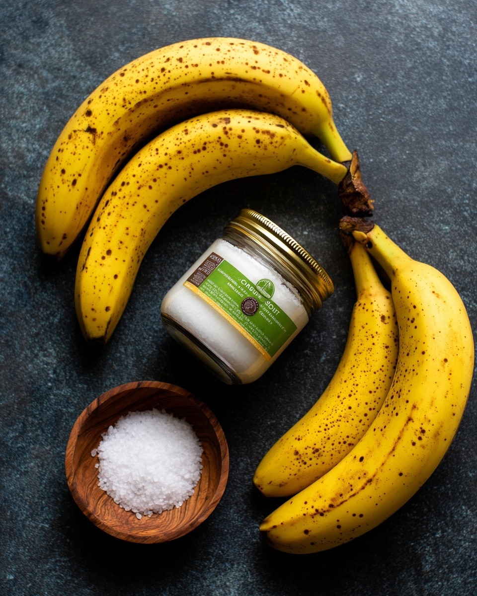 Four yellow bananas with spots are laid out on a dark textured surface. In the center, there is a clear glass jar with a golden metal lid filled with white coconut oil, showing a green and brown label. Above and to the right of the jar is a small wooden bowl filled with white salt. The bananas frame the jar and bowl from the top left, bottom right, and along the right side. photo taken with an iphone --ar 4:5 --v 7
